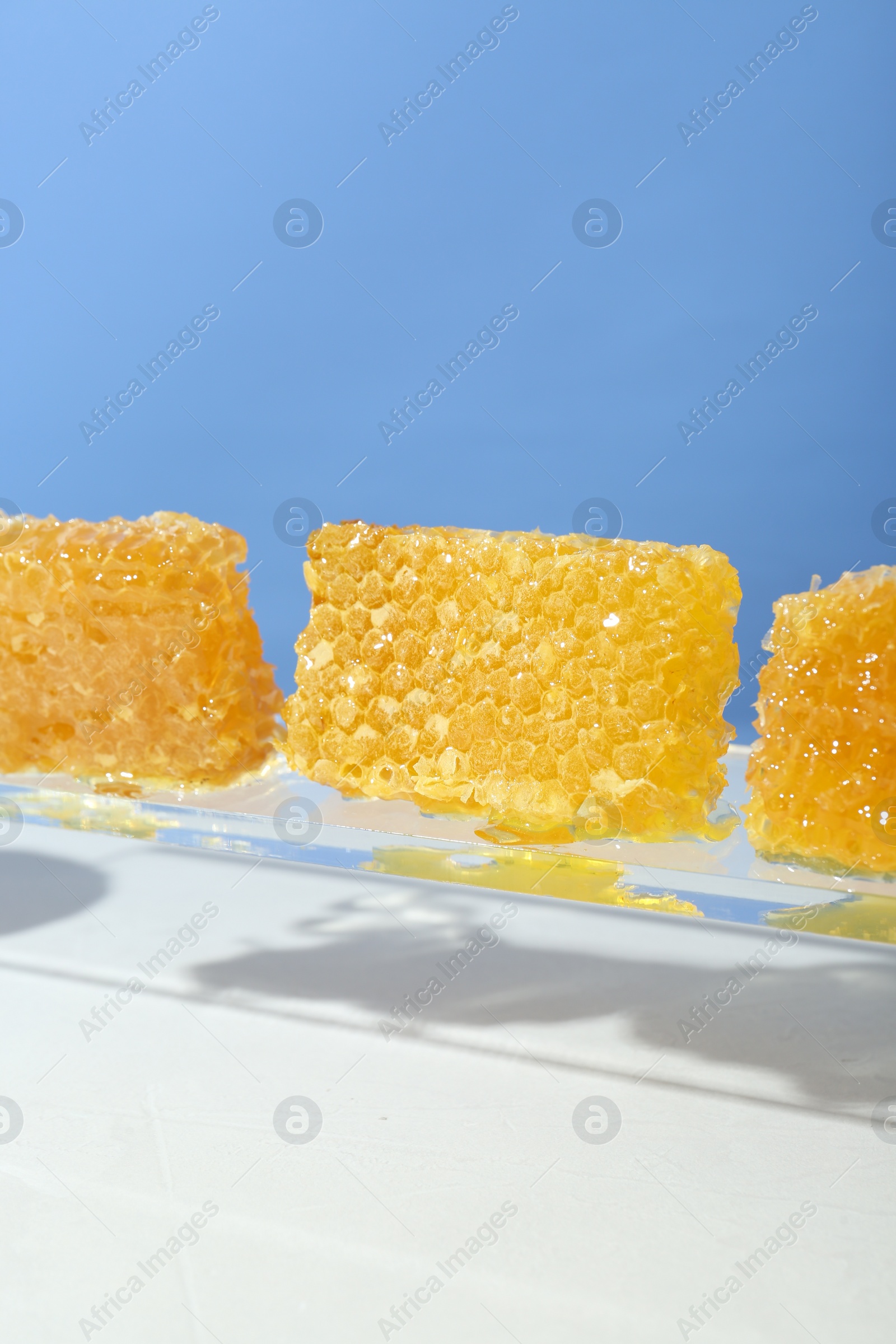 Photo of Natural honeycombs with tasty honey against light blue background