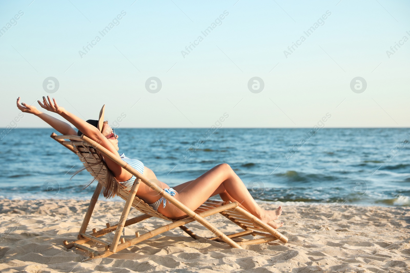 Photo of Young woman relaxing in deck chair on beach