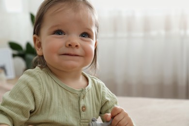 Happy baby girl with nibbler at home. Space for text