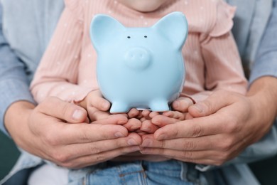Photo of Family budget. Little girl and her parents with piggy bank, closeup