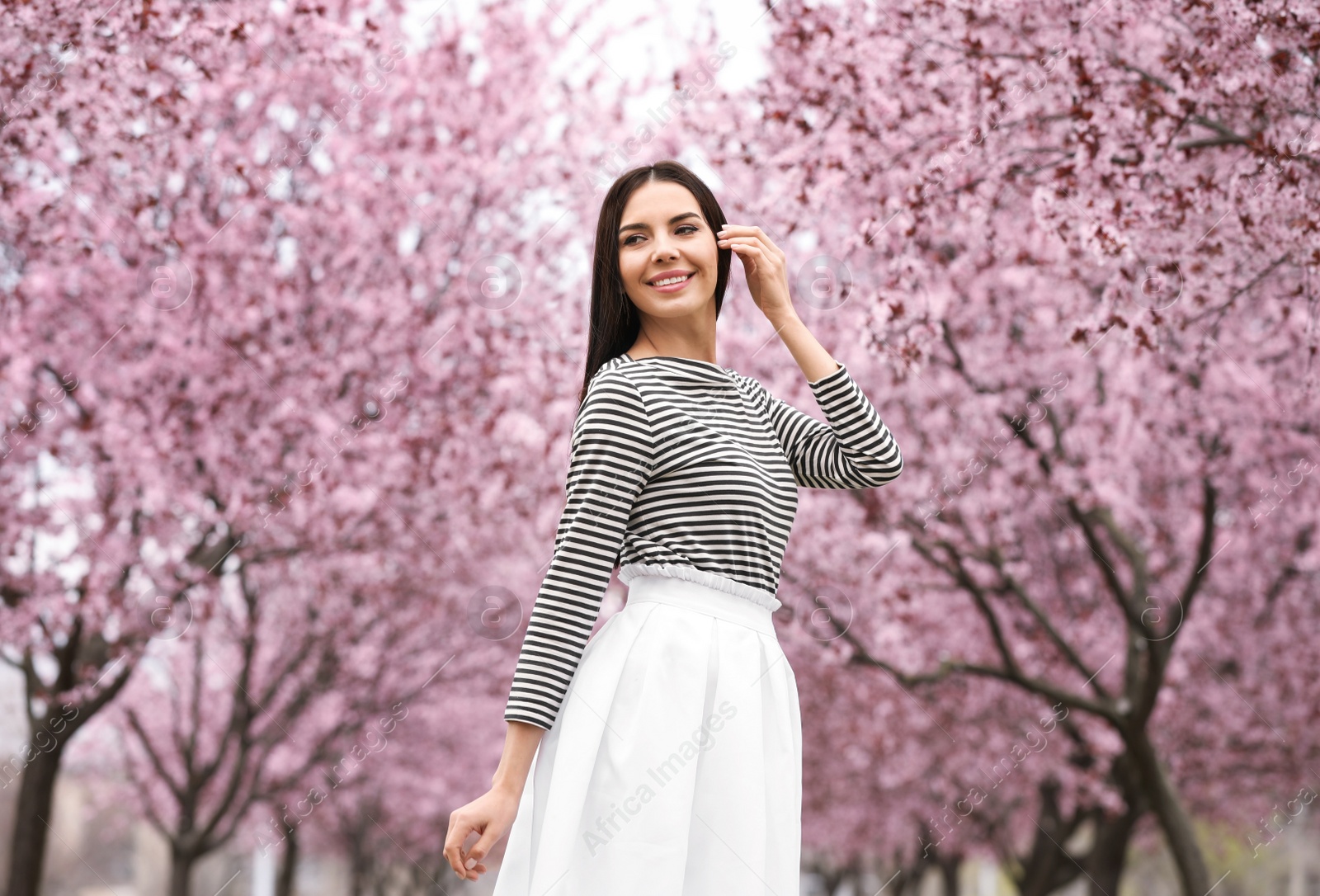 Photo of Pretty young woman in park with blooming trees. Spring look