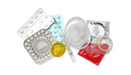 Photo of Contraceptive pills, condoms and thermometer isolated on white, top view. Different birth control methods
