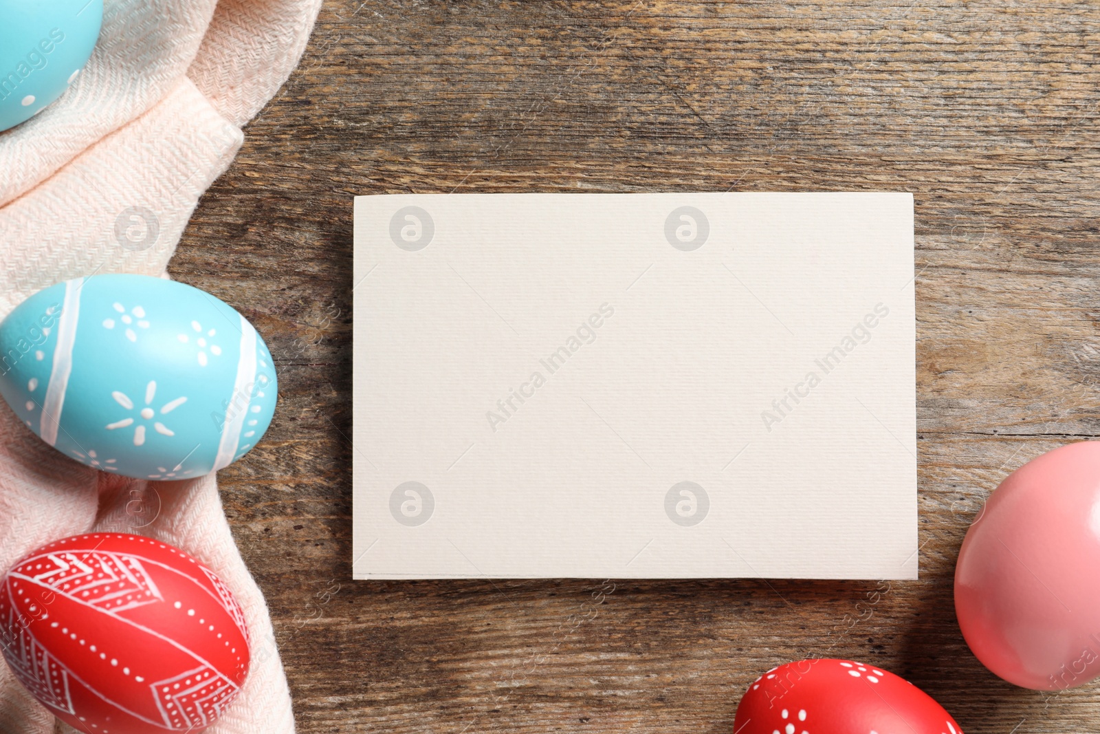 Photo of Flat lay composition of painted Easter eggs and card on wooden table, space for text