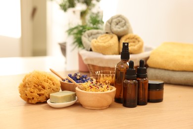 Photo of Dry flowers, loofah, soap bar, bottles of essential oils and jar with cream on wooden table indoors. Spa time