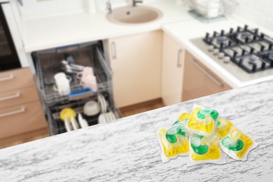 Image of Dishwasher detergent pods on white wooden table in kitchen