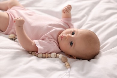 Photo of Cute little baby with toy lying on white sheets