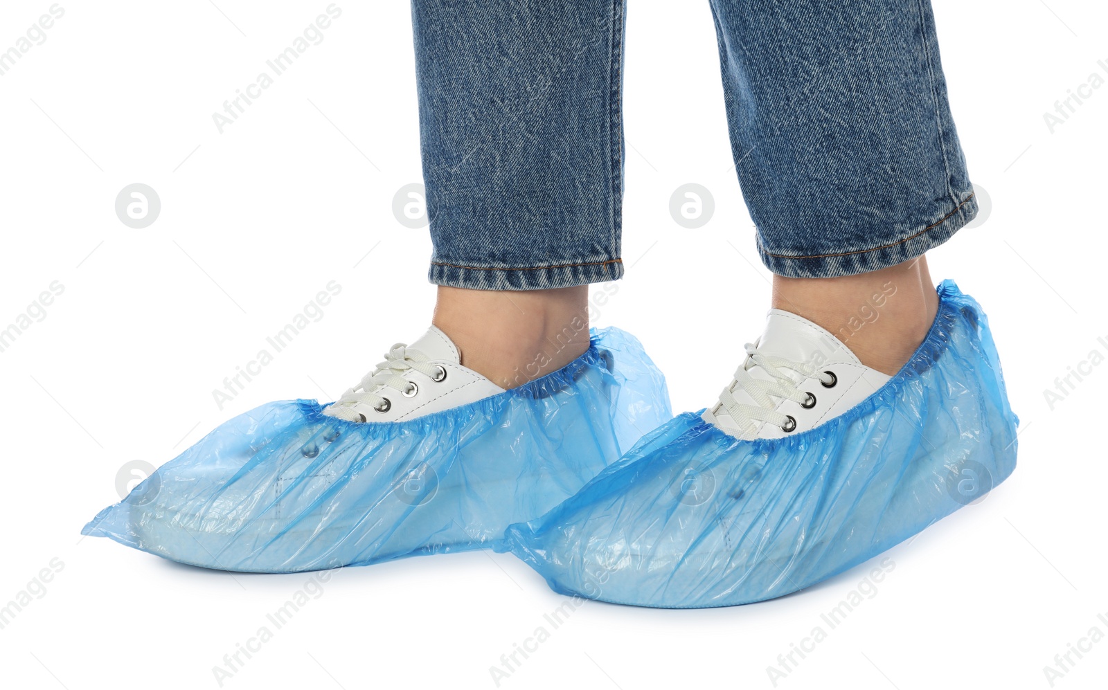 Photo of Woman wearing blue shoe covers onto her sneakers against white background, closeup