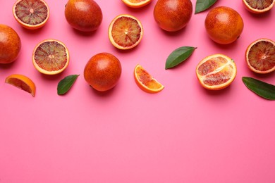 Photo of Many ripe sicilian oranges and leaves on pink background, flat lay. Space for text