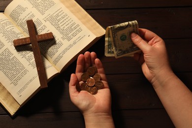 Donate and give concept. Woman with money, closeup. Bible and cross at wooden table, top view