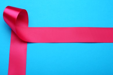 Photo of Beautiful pink ribbon on light blue background, top view