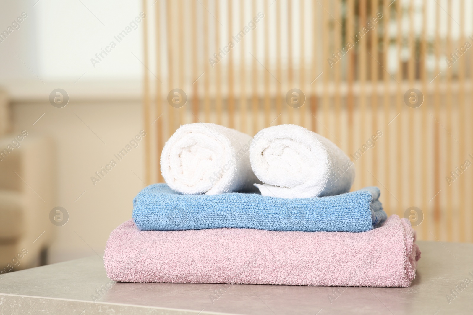 Photo of Soft folded terry towels on light gray table indoors