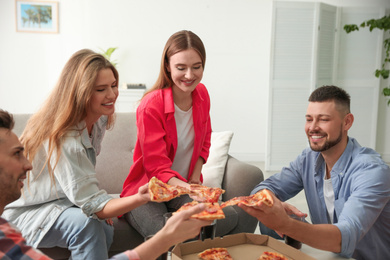 Group of friends eating tasty pizza at home