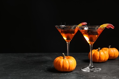 Decorated glasses with drinks on grey table, space for text. Halloween celebration