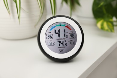 Photo of Digital hygrometer with thermometer on white table, closeup