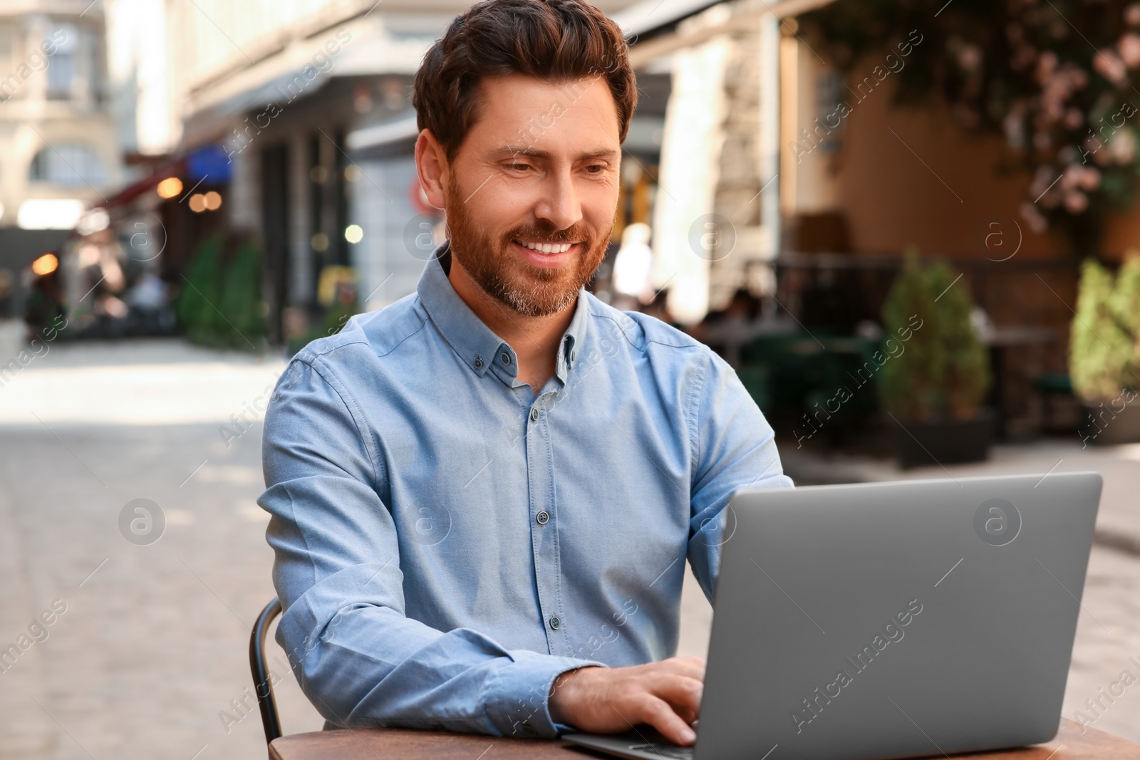 Photo of Man working on laptop at table in outdoor cafe