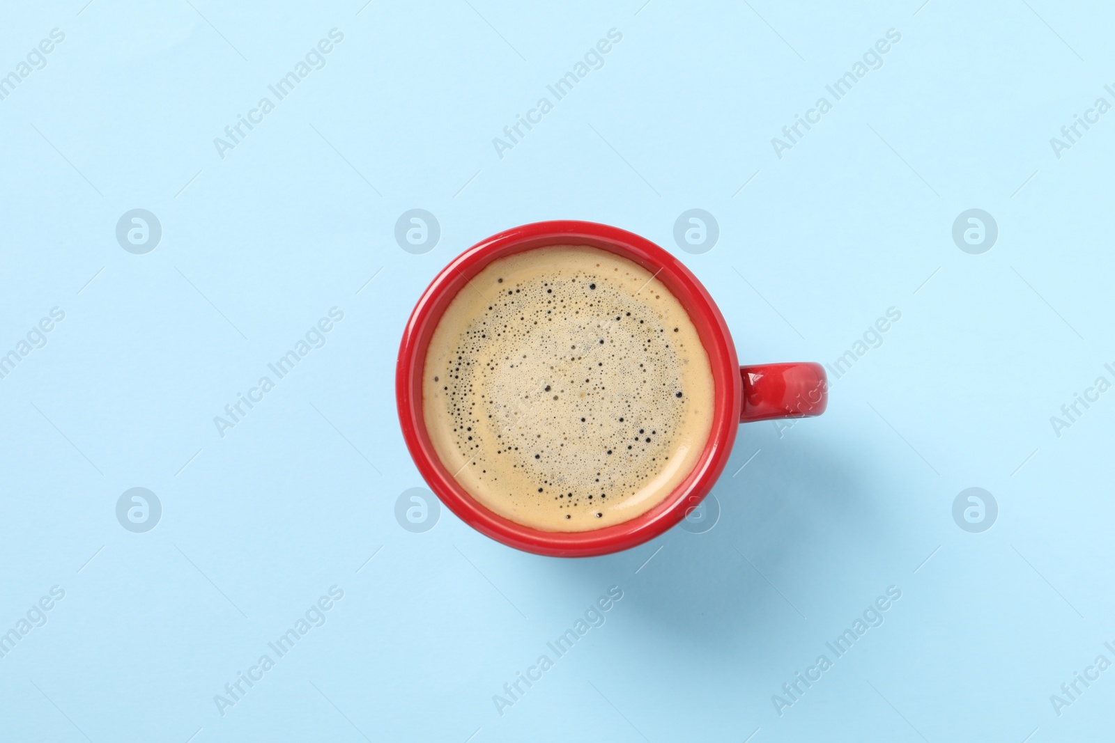 Photo of Tasty coffee in cup on light blue background, top view