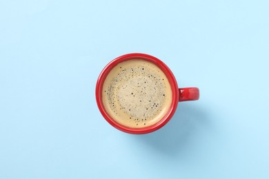 Photo of Tasty coffee in cup on light blue background, top view