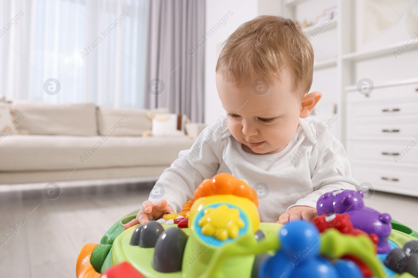 Photo of Cute little boy in baby walker at home, space for text