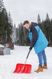 Photo of Man removing snow with shovel near house