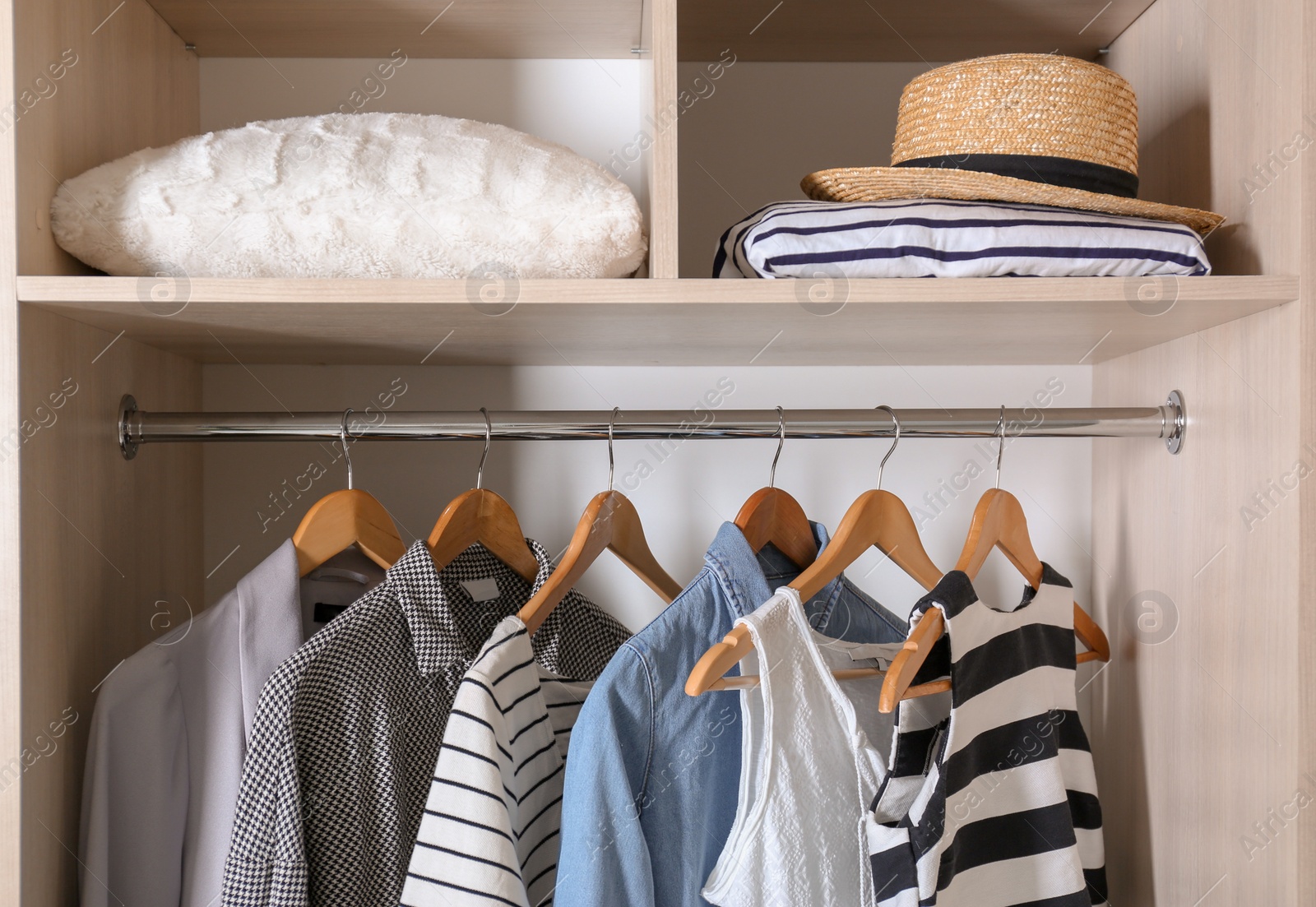 Photo of Collection of stylish clothes and pillow in wardrobe closet