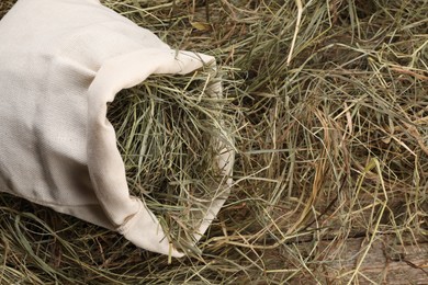 Photo of Dried hay in burlap sack on wooden table, top view