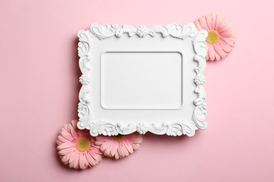 Photo of Empty photo frame and flowers on color background, top view. Space for text