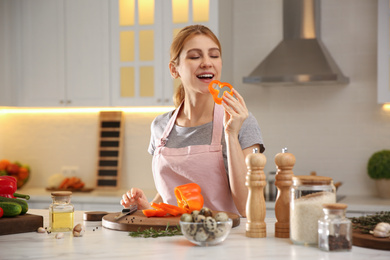 Young woman cooking at table in kitchen