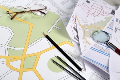 Office stationery and eyeglasses on cadastral maps of territory with buildings