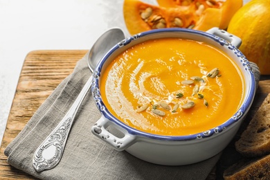 Photo of Bowl with tasty pumpkin soup served on table
