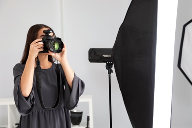Photo of Young woman with professional camera in photo studio