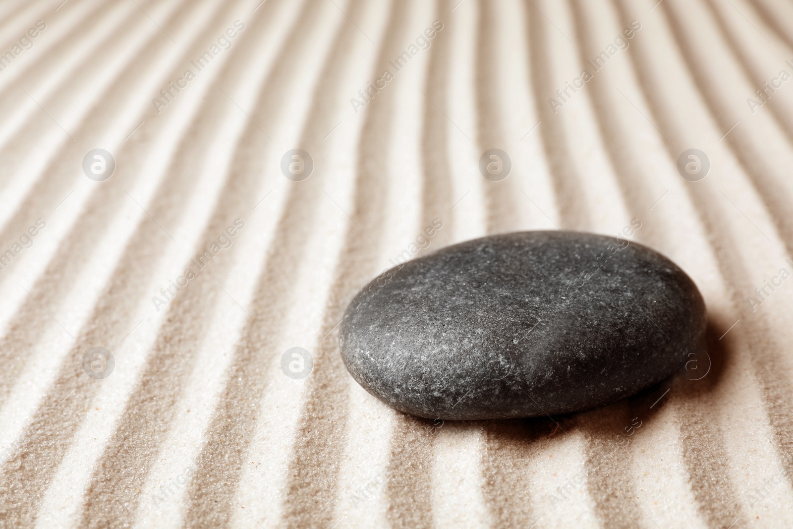 Photo of Zen garden stone on sand with pattern, space for text. Meditation and harmony