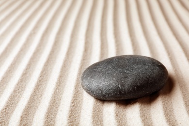 Photo of Zen garden stone on sand with pattern, space for text. Meditation and harmony