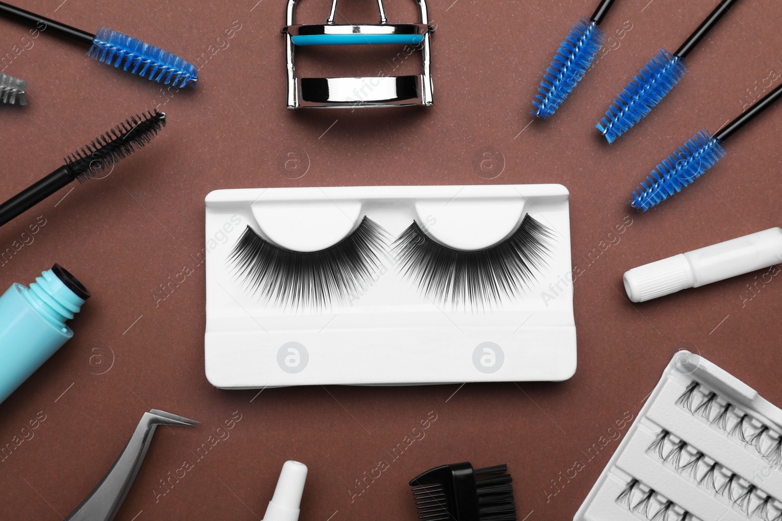 Photo of Flat lay composition with fake eyelashes, brushes and tools on brown background