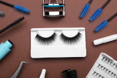 Flat lay composition with fake eyelashes, brushes and tools on brown background