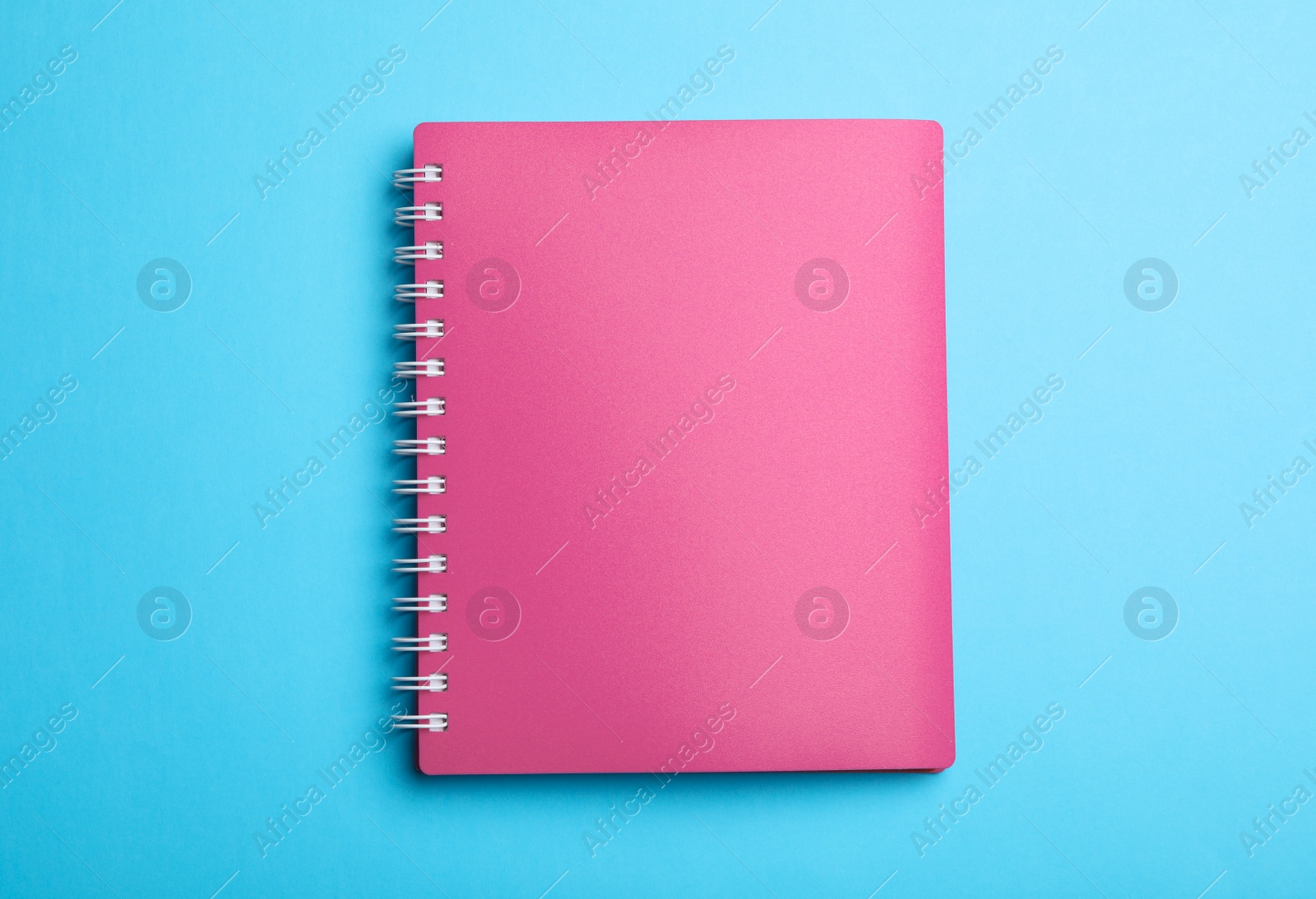 Photo of Stylish pink notebook on light blue background, top view