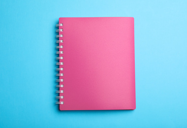 Stylish pink notebook on light blue background, top view