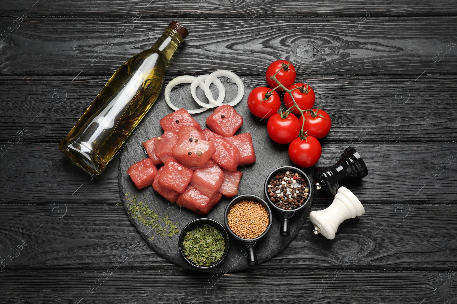 Photo of Raw beef meat and different ingredients for cooking delicious goulash on black wooden table, flat lay