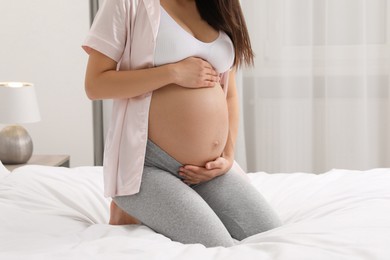 Photo of Pregnant woman on bed at home, closeup