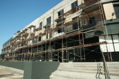 Blurred view of unfinished building with scaffolding against blue sky