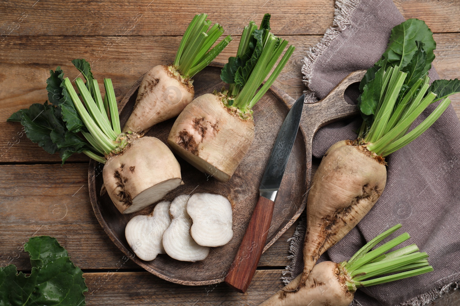 Photo of Whole and cut sugar beets on wooden table, flat lay