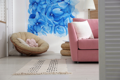 Photo of Stylish living room with blue flowers painted on wall. Floral pattern in interior design