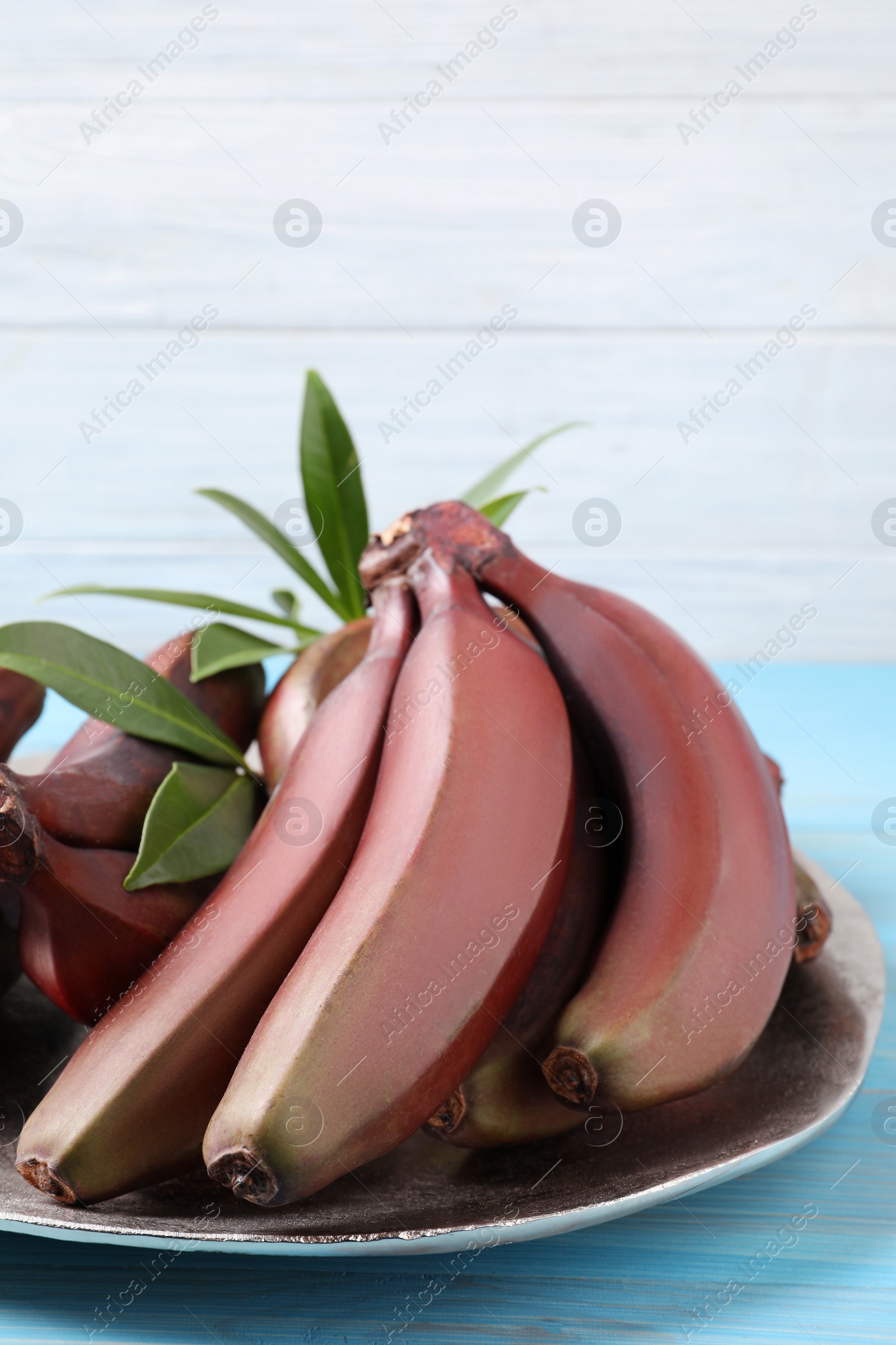 Photo of Tasty red baby bananas on light blue table, closeup