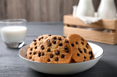 Delicious cookies with chocolate in bowl on black wooden table, space for text