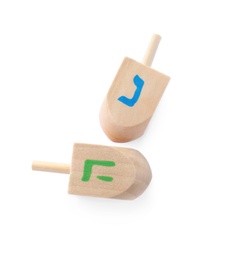 Wooden Hanukkah traditional dreidels with letters Nun and He on white background, top view