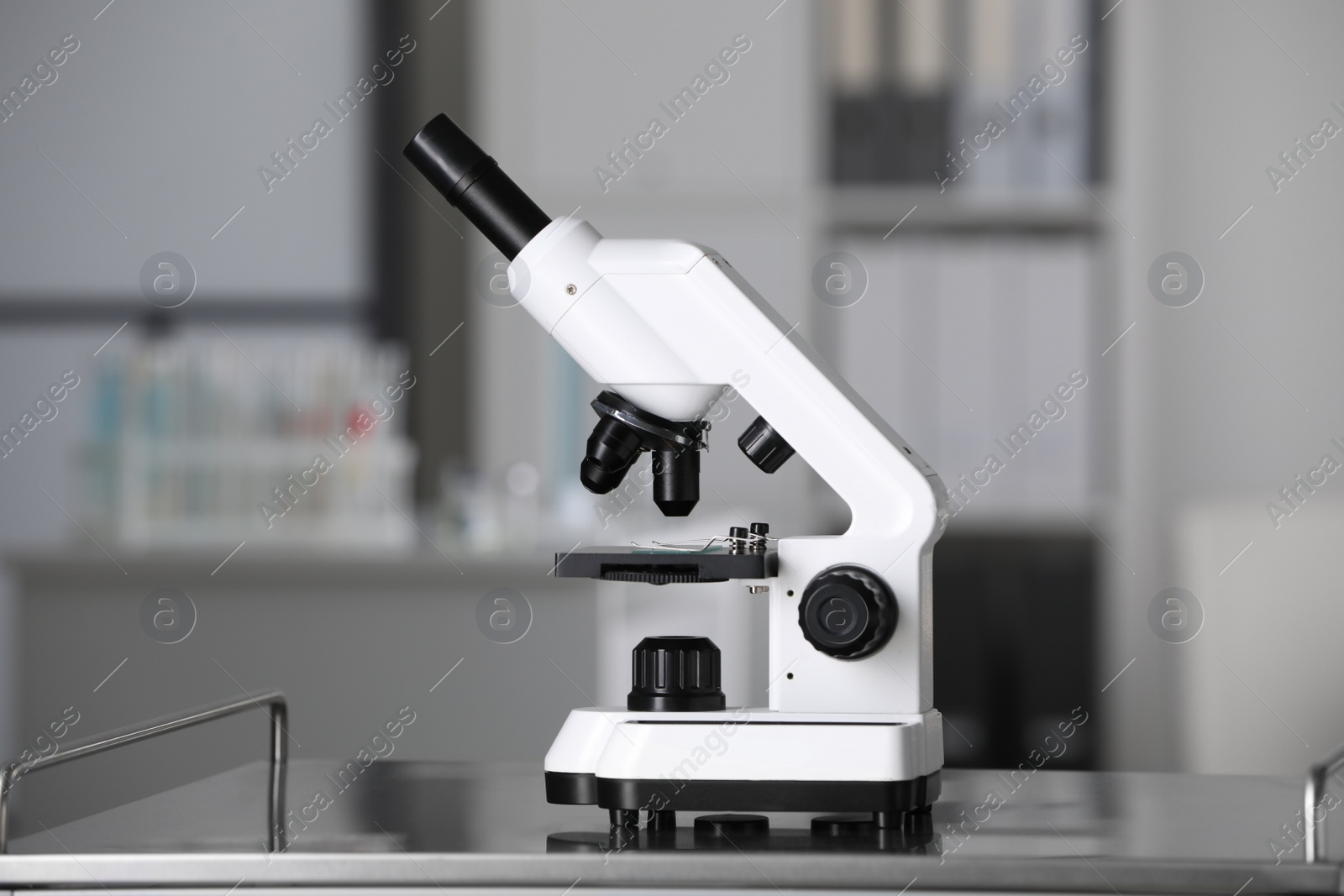 Photo of Modern medical microscope on metal table in laboratory