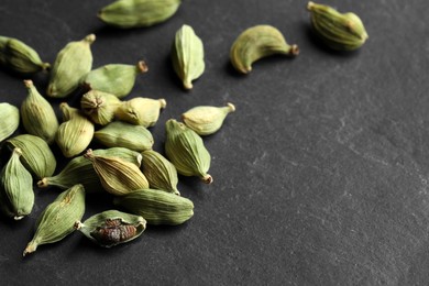 Photo of Pile of dry cardamom pods on black table, space for text