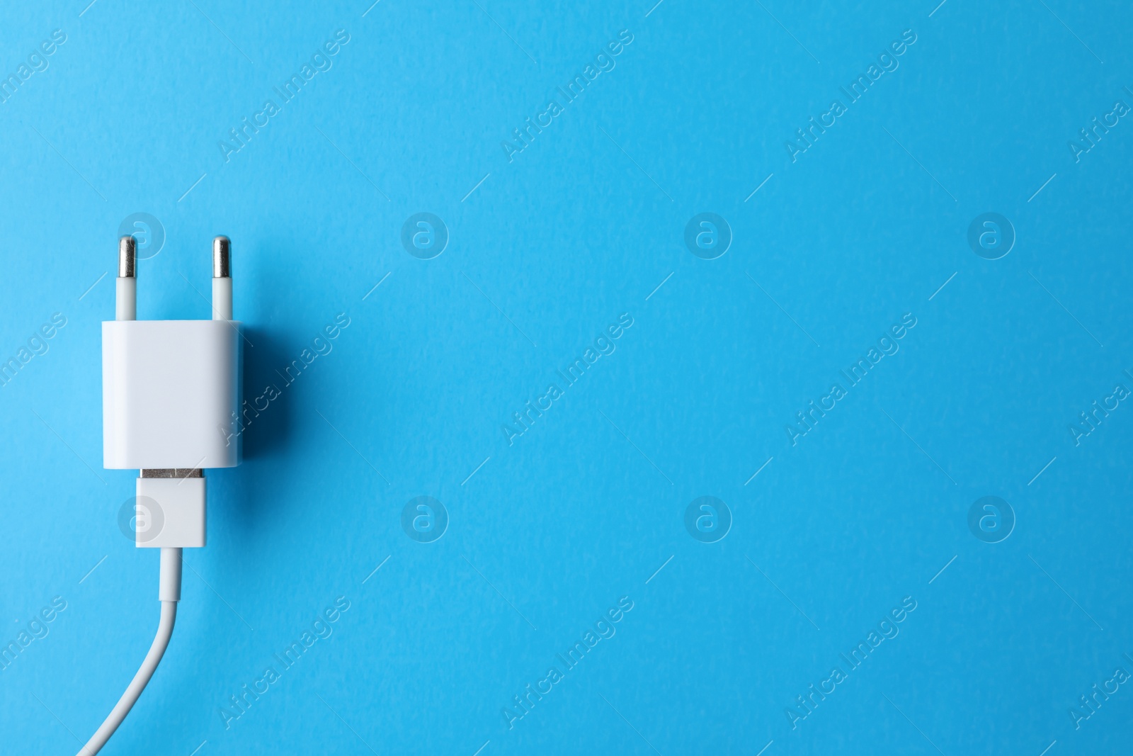 Photo of USB charger on light blue background, top view Space for text