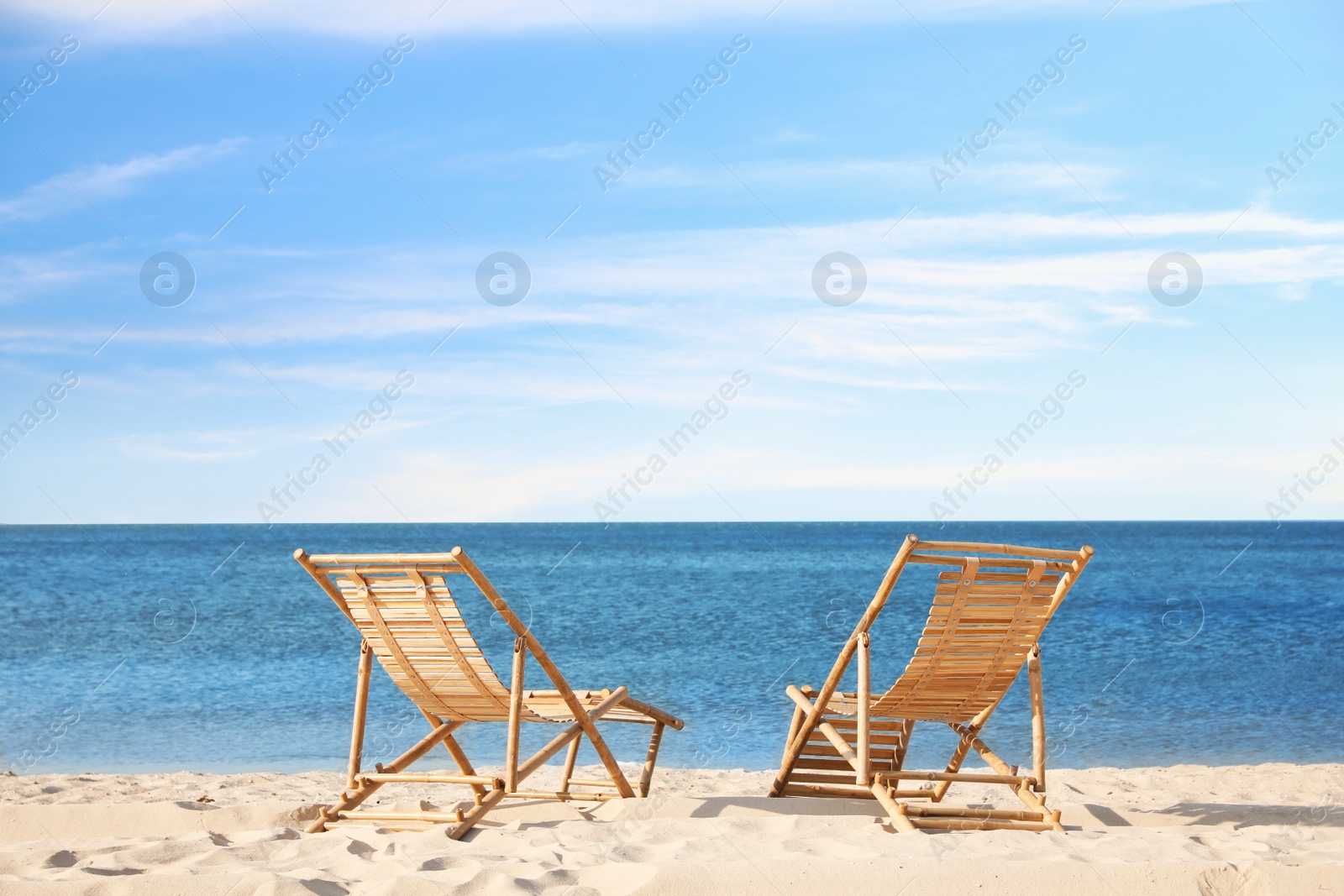 Photo of Wooden deck chairs on sandy beach near sea