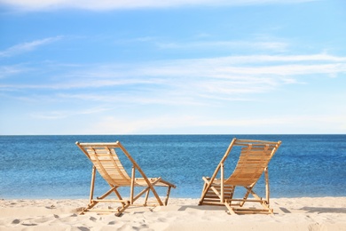 Photo of Wooden deck chairs on sandy beach near sea
