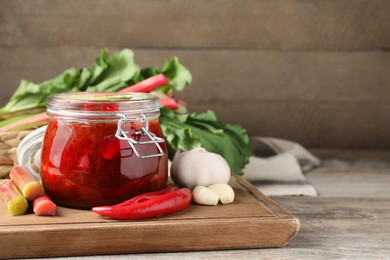 Photo of Tasty rhubarb sauce and ingredients on wooden table, space for text
